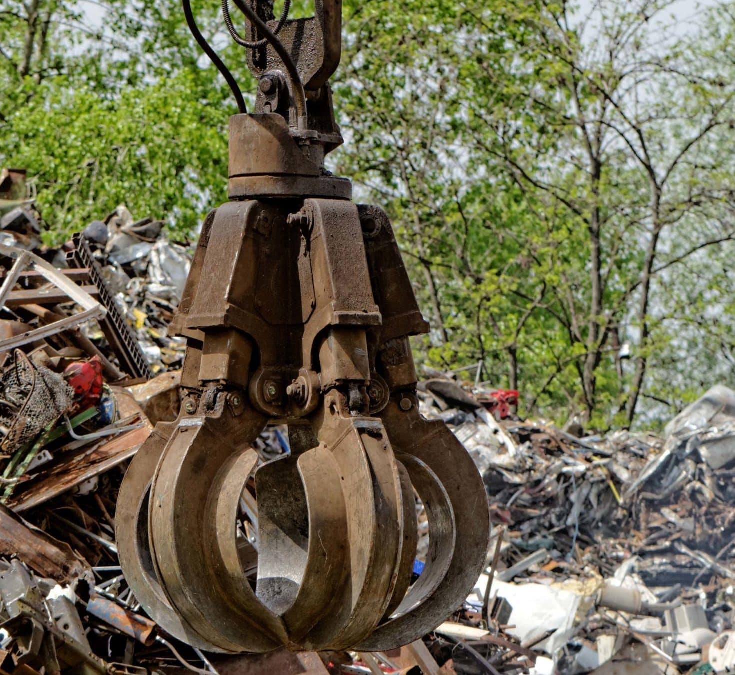 scrap metal grapple picking up metal in a junkyard