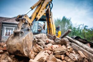 Yellow excavating operator crushing rock at construction site